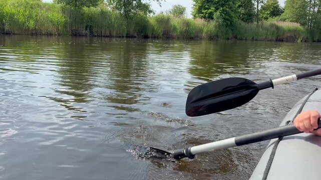 from an inflatable boat floating along the calm picturesque river. Two rowers are working the oars