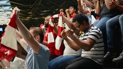 Soccer supporters celebrating victory with confetti, raised scarves and cheering crowd in stadium stands after dramatic live football match and team spirit. © DC Studio