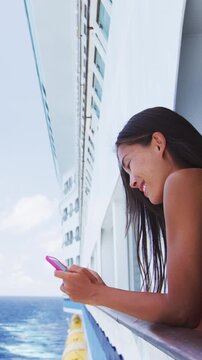 Vertical Cruise Ship Video. Phone woman texting on social media app on cruise ship travel vacation looking at display screen for reading on ocean background on balcony. Girl using phone on holiday.