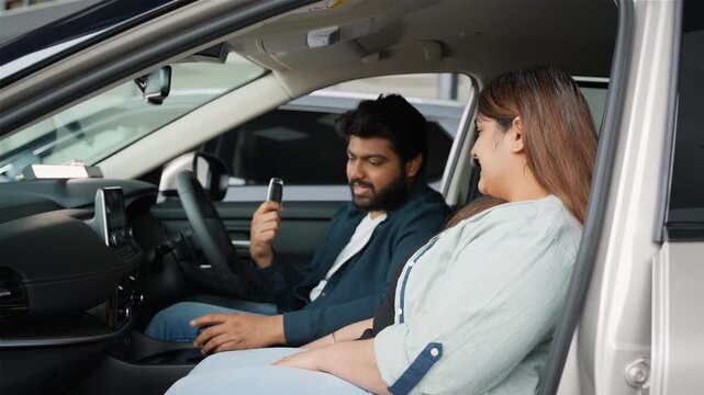 Happy indian couple buying new car at dealership showroom