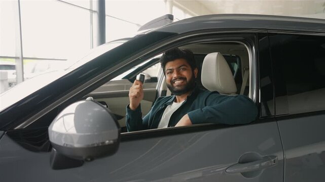 Happy indian man showing keys to his new car at dealership