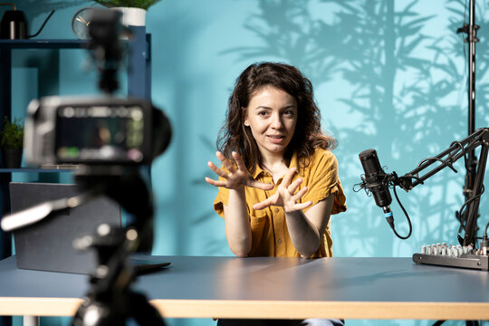 Enthusiastic internet show host hitting the record button on professional camera, using microphone to talk about today video topic with subscribers. Media star filming creative vlog.
