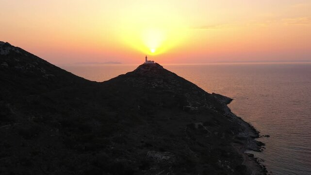 Knidos Lighthouse at sunset on tip of Dat&ccedil;a peninsula, aerial view over calm Aegean waters with golden sun reflection and distant islands. Aerial view, drone shot