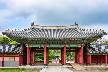 Obraz premium Traditional wooden main gate architecture under a dramatic sky at Changdeokgung Palace, Seoul, South Korea.