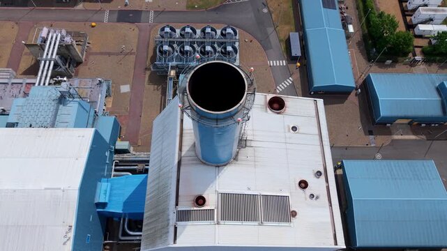 Aerial view of Palm Paper Industrial Factory showing industrial buildings with blue rooftops and a large circular chimney in King's Lynn, England, United Kingdom.