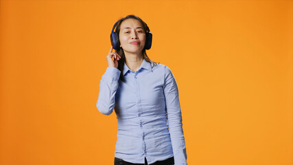 Happy person listens to music on headphones and dancing on camera, having fun with radio songs on audio headset, young joyful woman showing groovy dance moves and enjoying tunes