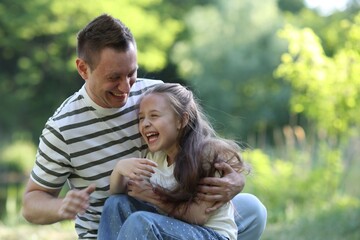 Fototapeta premium Smiling father and his daughter having fun outdoors on sunny day. Space for text