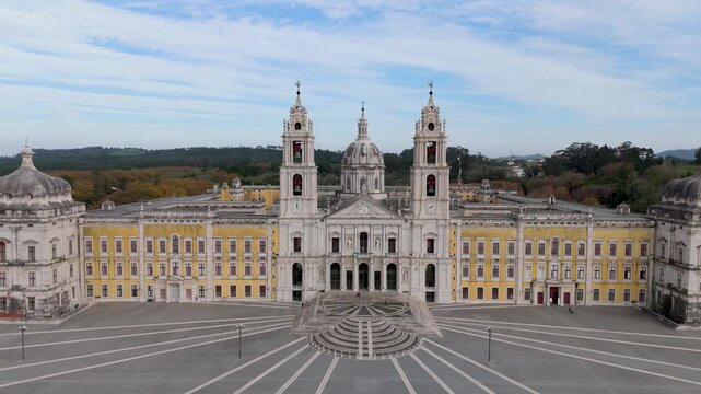 Aerial view of the baroque National Palace of Mafra with its grand facade, twin bell towers and central dome overlooking the large paved square in Mafra, Lisbon, Portugal.