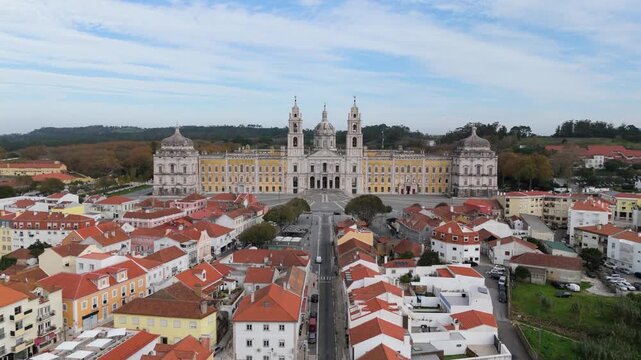 Aerial view of the monumental Palace of Mafra with its baroque towers and dome overlooking the red-roofed houses of the historic town in Mafra, Lisbon, Portugal.
