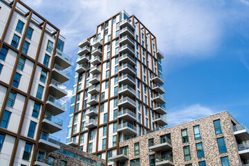 Fototapeta premium Modern residential apartment buildings with glass balconies under blue sky urban architecture