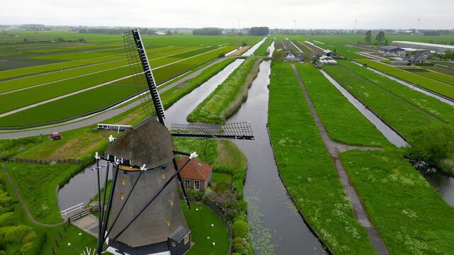 Traditional dutch windmill in a green polder landscape from above