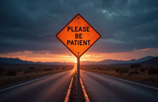 Orange sign reads please patient on highway at night. Warning road sign alerts drivers, communicates message. Cloudy dark sky above road disappearing into sunset. Drive safely obey rules enjoy route.