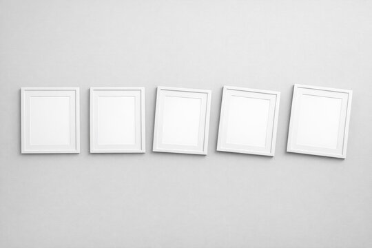 A collection of white picture frames mounted on a wall, ideal for displaying photos or artwork