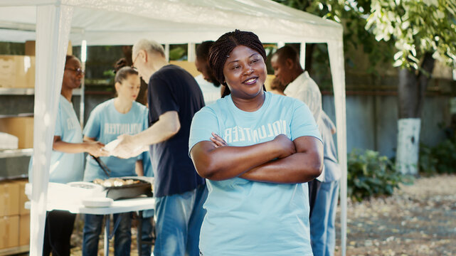 At food drive charitable event, African American female volunteer smiles and poses.