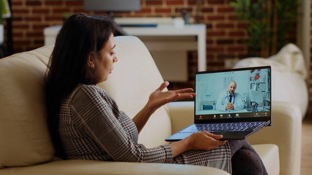 Patient sitting on couch, receiving treatment plan from medic during online videocall meeting after medical checkup, Indian person receiving prescription from GP in telemedicine call.