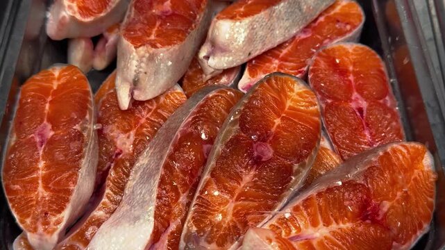 Fresh salmon steaks on a black tray, chilled at the market on the supermarket counter. Close-up