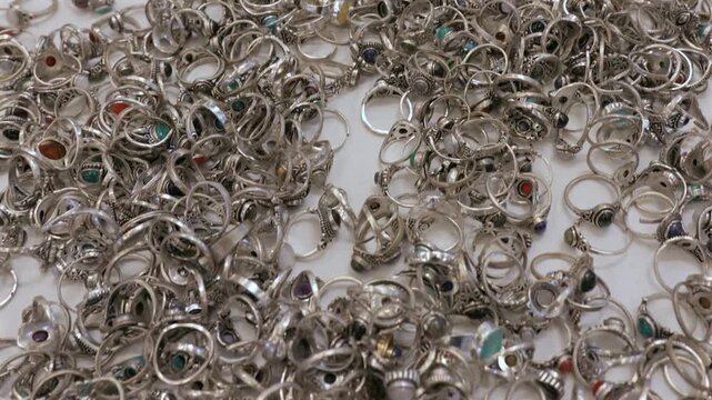 Handcrafted rings with natural gemstones displayed for sale on a white background in an Indian market
