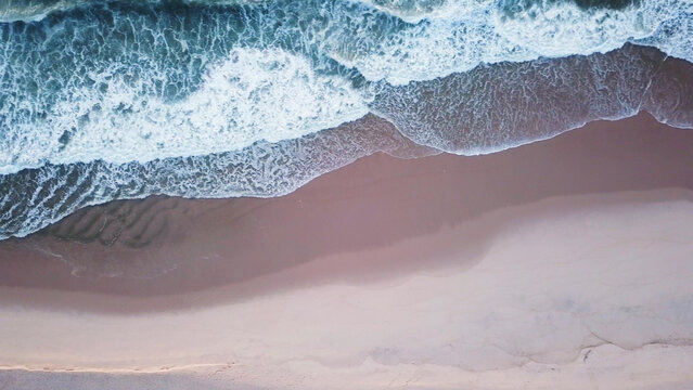 Aerial view of ocean waves hitting a sandy beach