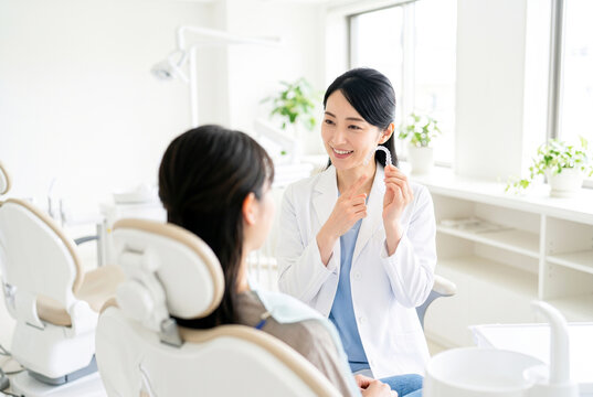 マウスピース矯正を説明する日本人女性歯科医師と説明を受ける女性患者の歯科カウンセリング風景
