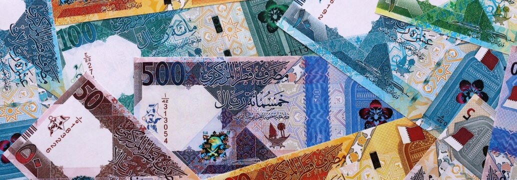 Qatari riyal money bills pile on table. Qatar banknotes of QAR currency close up.
