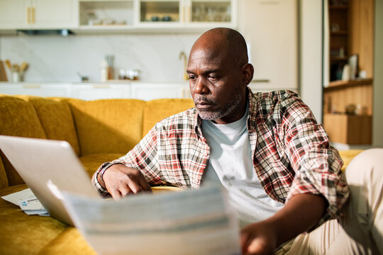 Middle-aged man paying bills online at home