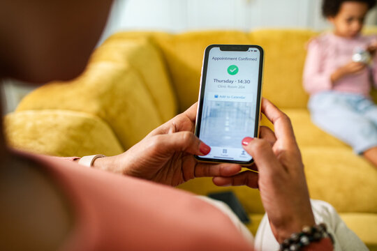 Mother checking healthcare appointment on smartphone at home