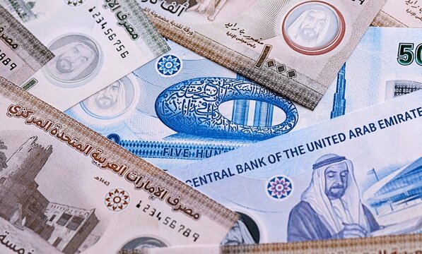 UAE dirham money bills pile on table. United Arab Emirates banknotes of AED currency close up.