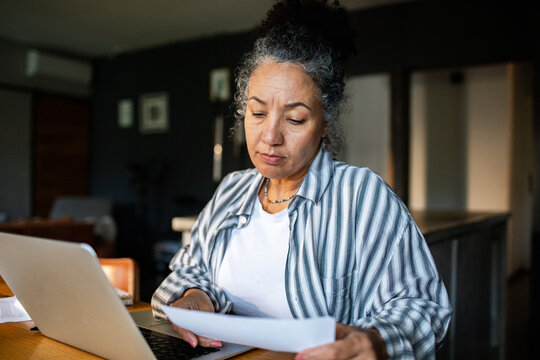 Mature woman reviewing paperwork at home office