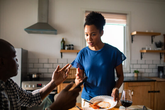 Concerned couple arguing in home kitchen after dinner