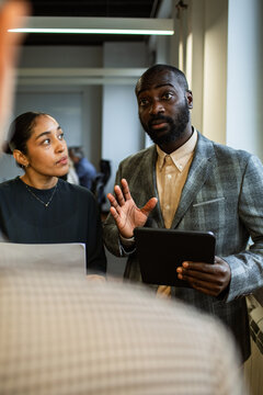 Two colleagues discussing project with tablet in modern office