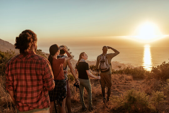 Group of hikers watching ocean sunset on coastal trail