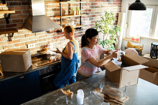 Two people unpacking boxes in new home kitchen