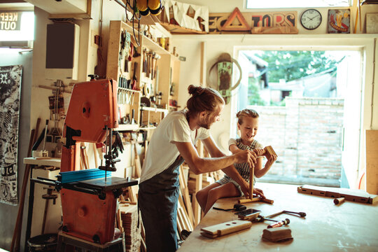 Father teaching daughter woodworking in home workshop