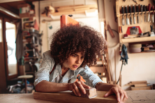 Young artisan sanding wood in workshop