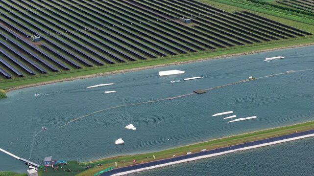 Aerial view of Fenland Aqua Park featuring wakeboarding obstacles and a large solar farm in Whittlesey, England, United Kingdom.