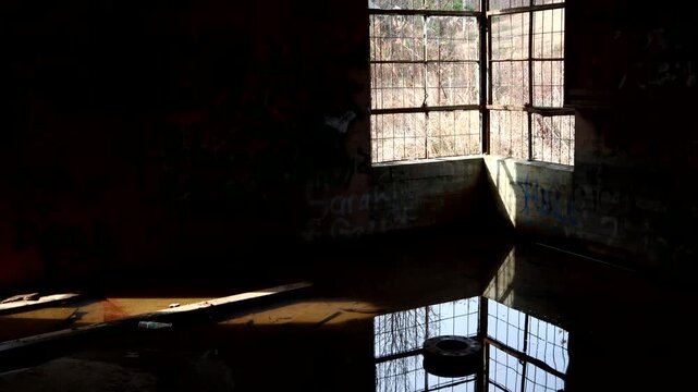 An old window creates a mood while reflected in the water on the floor of an abandoned building