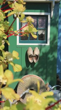 Traditional Dutch wooden clogs hanging on a rustic green cottage wall in a charming garden setting