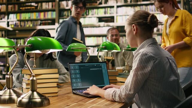 Student uses laptop with AI chatbot interface at library table, modern learning tool and virtual assistant with classmates studying nearby.
