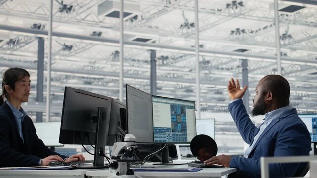 Diverse men and women in microchip factory office working together to optimize production, teamwork coworkers using computer to improve semiconductor processing efficiency for semiconductor research.