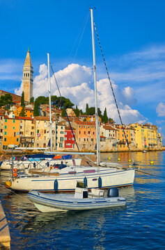 Antique town Rovinj, Istria, Croatia. Sea morning with yachts and boats by pier. High tower on hill with old Mediterranean houses. Picturesque sky with clouds.