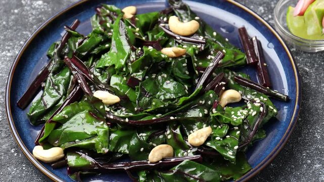 Woman squeezing lime juice onto delicious salad at grey table, closeup