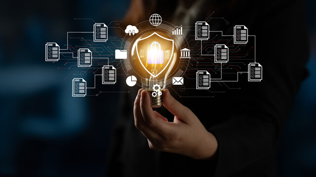 A businessperson holds a glowing light bulb featuring security symbols, signifying innovation in data protection and digital transformation in a modern business setting. Ledger