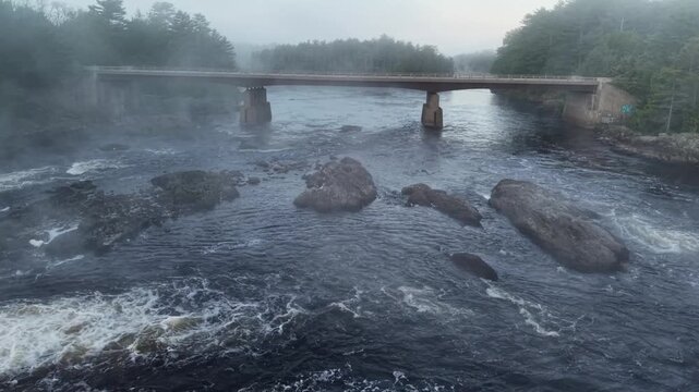 Penobscot River Old Town, Maine on a cold foggy spring morning dronie shot of the the bridge, river, fog and dam