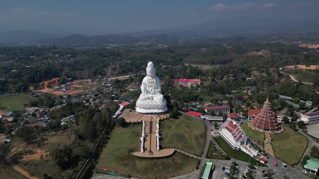 Aerial view of the majestic white Guan Yin statue at Wat Huay Pla Kang temple complex surrounded by lush hills and traditional architecture in Chiang Mai, Chiang Mai, Thailand.