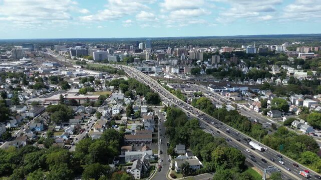 Aerial 4K drone tracking shot of Interstate 95 and train tracks leading into downtown Stamford Connecticut skyline