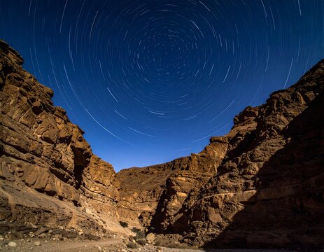 Night landscape looking down the multi-layered canyons of Khuren Khaniin Khets in Mongolia. Concentric circular star trails rotate over sharp geological strata. Cinematic 8k photo.