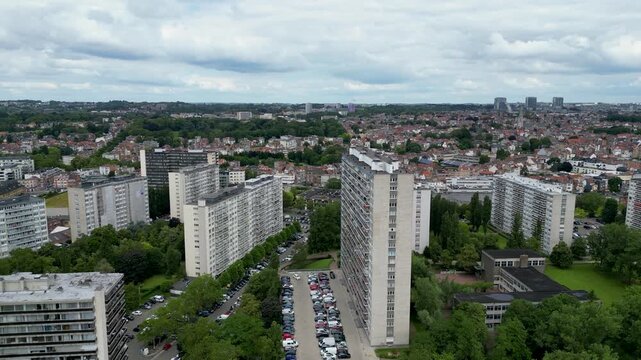 Aerial view of high-rise residential apartment blocks with parking lots and green trees under a cloudy sky in Anderlecht, Brussels, Belgium.