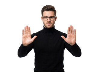 Fototapeta premium A young man in a black turtleneck sweater and glasses holds up his hands in a stop gesture on a white background.