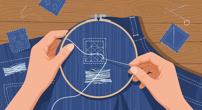 Hands mending denim fabric with needle and thread in an embroidery hoop.