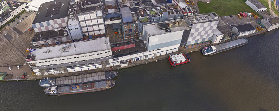 Wormer, Netherlands - 08 April 2026: Aerial view of the Ofi Cocoa factory De Moriaan with inland barges docked along the Zaan river under soft daylight.